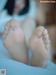 A close up of a person's bare feet on a bed.