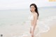 A woman in a white bikini standing on a beach.