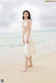 A woman in a white bikini standing on a beach.