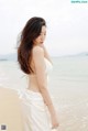 A woman in a white dress standing on a beach.