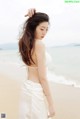 A woman in a white dress standing on a beach.