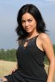 A woman in a black dress sitting in a field.