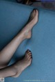 A woman's bare feet on a blue couch.