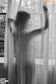 A naked woman standing in front of a window.