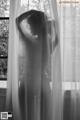 A naked woman standing in front of a window.