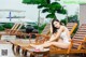 A woman in a white bathing suit sitting on a wooden lounge chair.