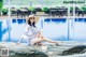 A woman sitting on a rock by a swimming pool.