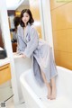 A woman in a bathrobe standing in a bathroom.