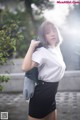 A woman in a white shirt and black skirt posing for a picture.