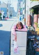 A woman leaning against a sign on the side of a street.