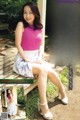 A woman in a pink top and white skirt sitting on a bench.