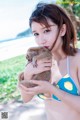 A woman in a bikini holding a small animal.