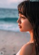 A woman standing on a beach looking out at the ocean.