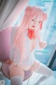 A woman with long pink hair sitting on a chair.