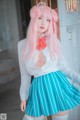 A woman with pink hair wearing a blue and white striped skirt.
