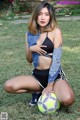 A woman sitting on the grass with a soccer ball.