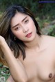 A naked asian woman posing in the woods. 