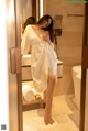 A woman in a white robe standing in a bathroom.