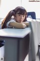 A young woman leaning on a desk in a classroom.