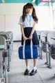 A woman in a school uniform holding a blue bag.