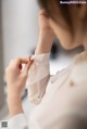 A woman in a white shirt is putting on a ring.