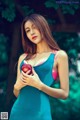 A woman in a blue dress holding an apple.