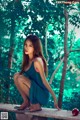 A woman in a blue dress sitting on a wooden bench.