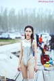 A woman in a silver bodysuit standing next to a boat.