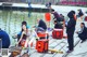 A group of people sitting on a dock next to a body of water.