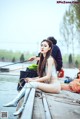 A woman sitting on a dock next to a body of water.