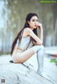 A woman sitting on a wooden bench in a silver outfit.