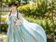 A woman in a blue and orange hanbok is posing for a picture.