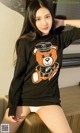 A woman wearing a black sweater with a teddy bear on it.