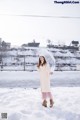 A woman standing in the snow holding an umbrella.