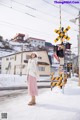 A woman standing in the snow next to a railroad crossing.