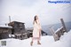 A woman standing on a snow covered beach next to the ocean.