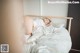 A woman laying on top of a bed covered in white sheets.