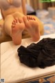 A woman sitting on top of a table next to a pair of black panties.