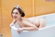 A woman in a pink bikini laying in a bathtub.