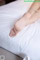 A woman laying on top of a bed with her feet up.