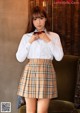 A woman in a white shirt and plaid skirt posing for a picture.