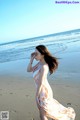 A woman in a long dress standing on a beach.