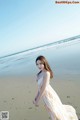 A woman in a long dress standing on a beach.