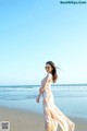 A woman in a long dress standing on a beach.