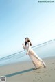 A woman in a long dress standing on a beach.