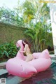 A woman in a bikini sitting on an inflatable flamingo.