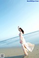 A woman in a long dress standing on a beach.