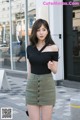 A woman in a black top and green skirt is walking down the street.