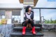 A woman sitting on the steps of a building with red boots.