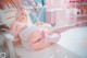 A woman in a pink and white outfit laying on a white chair.